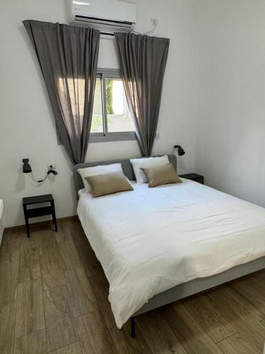 a bedroom with a large white bed and a window at בית בעמק בעיצוב מודרני וחמים in Bet Sheʼan