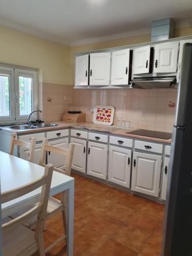 a kitchen with white cabinets and a table and chairs at Apartamento T2 Ansiães-Douro in Carrazeda de Anciães