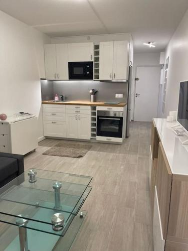une cuisine avec des armoires blanches et une table en verre dans l'établissement T1 standing LA DÉFENSE - 10 min PARIS & U ARENA, à Courbevoie