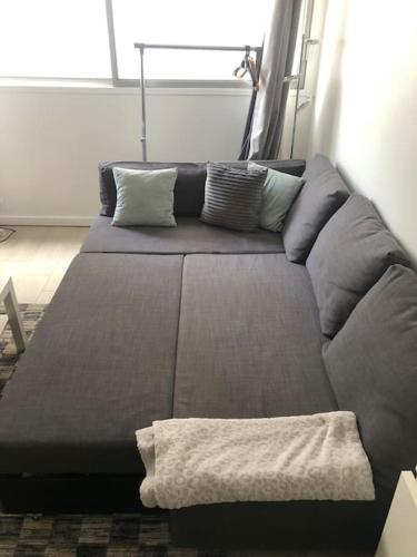 - un canapé brun avec des oreillers dans l'établissement T1 standing LA DÉFENSE - 10 min PARIS & U ARENA, à Courbevoie