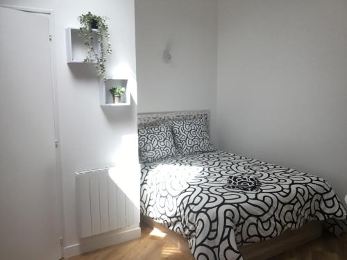 a bedroom with a bed with a black and white comforter at Appartement idéalement situé in Les Sables-dʼOlonne