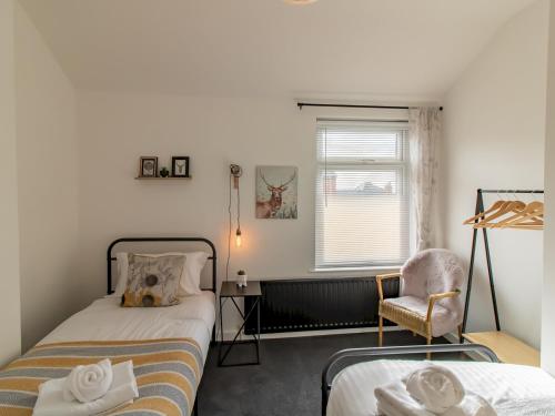 a bedroom with two beds and a chair and a window at Pass the Keys City Convenience in Stanley
