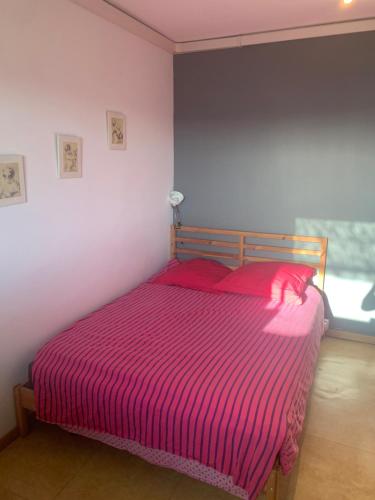 - une chambre avec un lit et une couverture rayée rose dans l'établissement Joli appartement avec belle terrasse, à Marseille