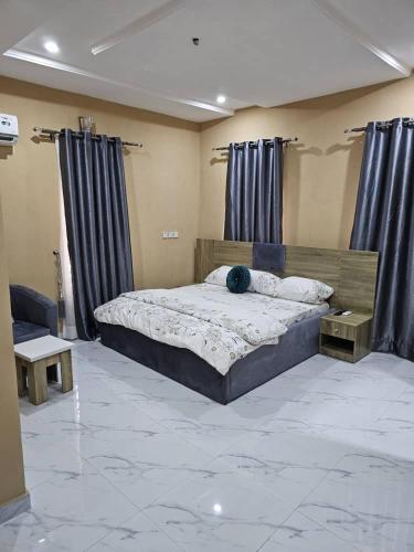 a bedroom with a large bed with blue curtains at Skyline Apartments in Lagos
