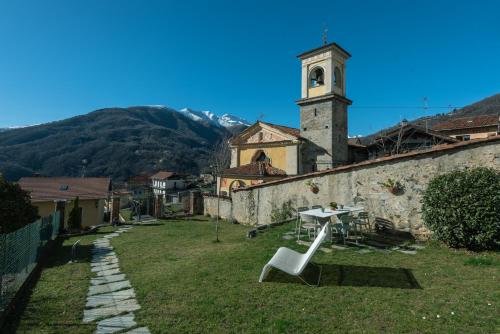 a white chair sitting in the yard of a building with a clock tower at Elegante e Panoramico Bilocale La Libellula in Tavigliano