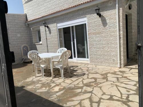 a white table and chairs on a patio at Logement spacieux 10personnes - Location Azeffoun Ait Chafaa-11000da in Azeffoun