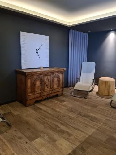 a room with a table and a chair and a clock at Hotel Zirmes in Moena