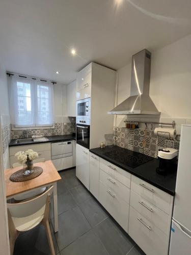 une cuisine avec des armoires blanches et une table en bois dans l'établissement Appartement Dalayrac, à Fontenay-sous-Bois