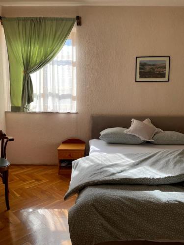 a bedroom with a bed with a green curtain and a window at Green House Livno in Livno