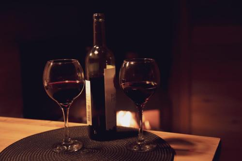 two wine glasses on a table with a bottle of wine at Cabanas dos Plátanos in Gramado