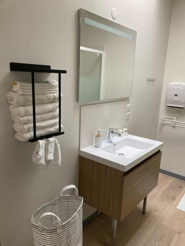 une salle de bain avec un lavabo, un miroir et des serviettes dans l'établissement Joli petit appartement, à Eymet