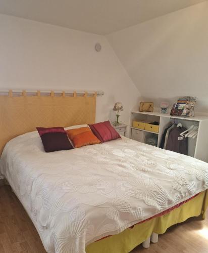 - une chambre avec un grand lit blanc et des oreillers colorés dans l'établissement Studio à la campagne proche de Honfleur, à Saint-Gatien-des-Bois