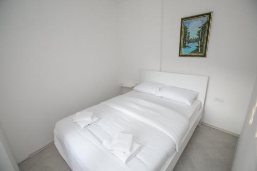 a white bed in a room with a picture on the wall at Vila Varagic in Budva