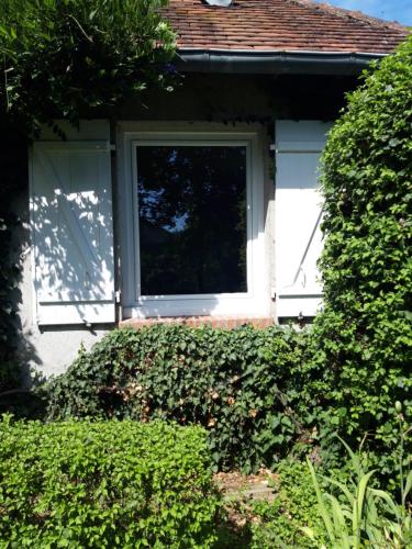 une maison blanche avec une fenêtre et une haie dans l'établissement chambre d'hôte, à Saint-Rémy-en-Rollat