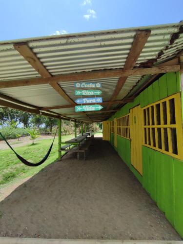 a green building with a metal roof and benches at Habitación compartida con tres comidas incluidas y dos horas de electricidad diarias in Drake