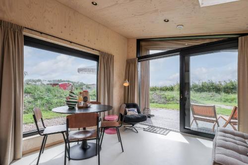 ヴェストカペレにあるHello Zeeland - Tiny House Zeeuwse Liefde 15のテーブルと椅子、大きな窓が備わる客室です。