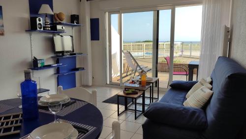 un salon avec un canapé bleu et un balcon dans l'établissement Ty Trugar T2 classé 3 étoiles face à l'océan piscine tennis, à Guidel