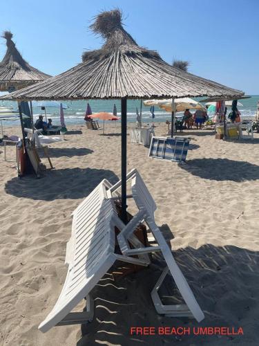 a beach with chairs and an umbrella on the sand at Mahane in Tirana
