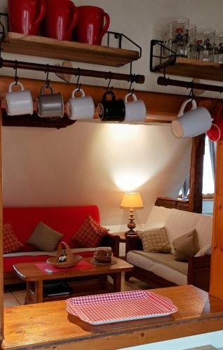 a living room with a red couch and a table at Un balcon sur les toits in Beblenheim