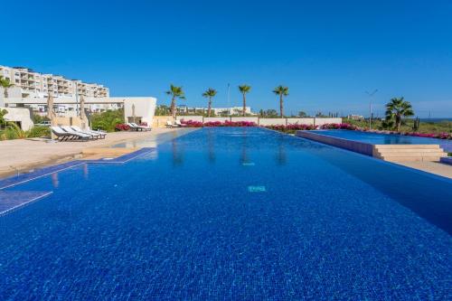 a large swimming pool in a resort with palm trees at Luxury Condo with Ocean View, Balcony, and Pool in Cabo San Lucas