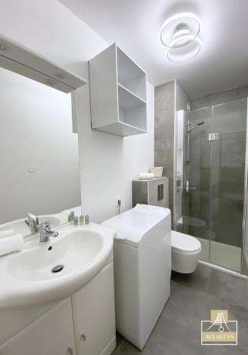 une salle de bain blanche avec un lavabo et des toilettes dans l'établissement LE SAOMA, studio cabine, parking privé, climatisation, à La Grande Motte