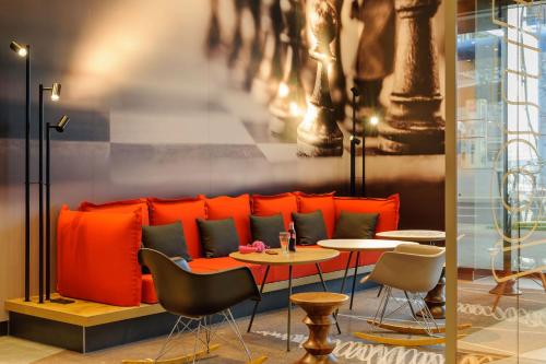 a restaurant with an orange couch and tables and chairs at Ibis Berlin Hauptbahnhof in Berlin