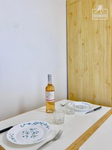 une bouteille de vin et deux assiettes sur une table dans l'établissement LE SAOMA, studio cabine, parking privé, climatisation, à La Grande Motte