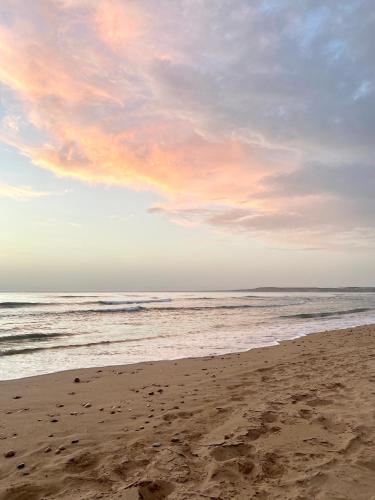 a beach with a cloudy sky and the ocean at Adam house in Essaouira