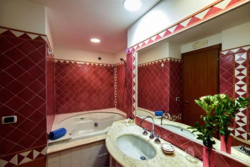 a bathroom with a tub and a sink and a mirror at Hotel Graal in Ravello