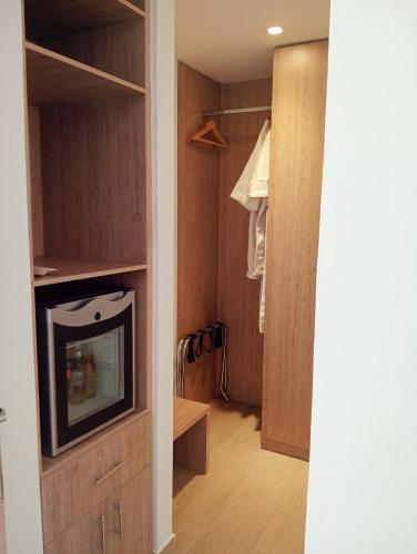a room with a tv and a closet with a door at Hotel Lomas 10 Medellin in Medellín