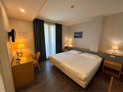 a hotel room with a large bed and a desk at Hotel Ristorante Primavera in Godega di SantʼUrbano