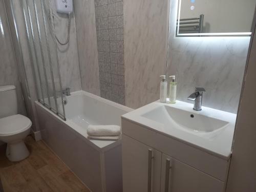 a bathroom with a sink and a tub and a toilet at Alnwick Town Centre Apartment in Alnwick