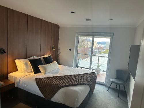 a bedroom with a large bed and a window at City fringe modern apartment with car parking in Hobart
