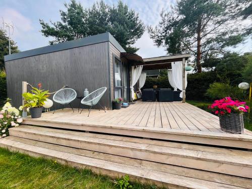 a tiny house with two chairs on a wooden deck at Lawendowe Zacisze 2 in Odargowo