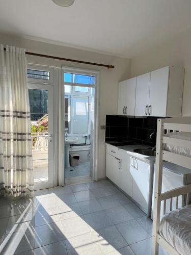 a kitchen with white cabinets and a sliding glass door at Mimi's Apartments in Vlorë
