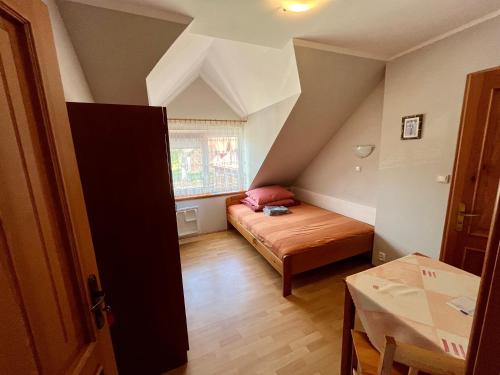 a small attic room with a bed and a table at Pokoje gościnne Pod bocianami in Stegna