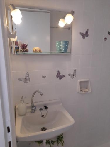 a bathroom with a sink and butterflies on the wall at Heraklion Centre Experiene in Heraklio