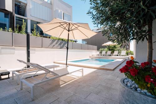 an umbrella and a chair next to a swimming pool at Adria Concept Suites in Zadar