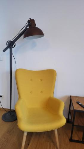 a lamp and a yellow chair next to a table at Quartier No. 7 - Serviced Living in Grödig