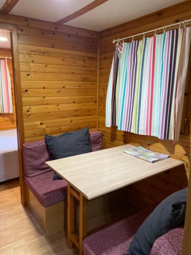 a room with a wooden table and purple chairs at Camping Forcanada in Era Bordeta
