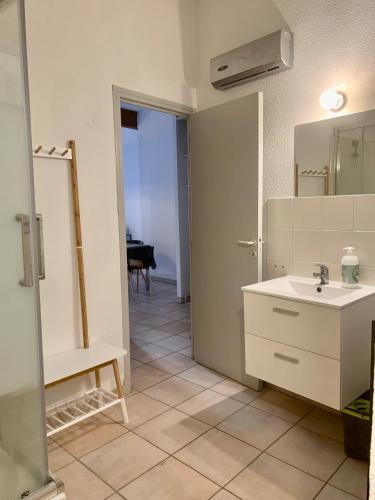 une salle de bain blanche avec un lavabo et un miroir dans l'établissement COSY CENTRAL - Charme au Centre - Wifi, à Perpignan