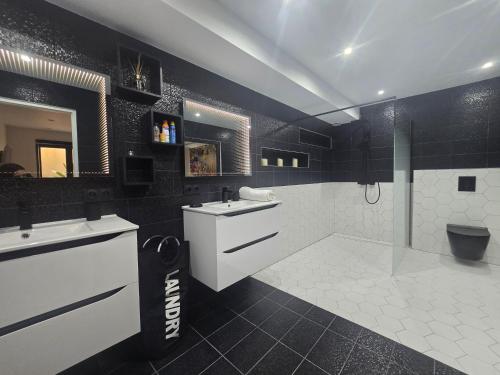 La salle de bains en noir et blanc est pourvue d'un lavabo et d'une douche. dans l'établissement Villa Ronsard - vue mer, à Fréjus