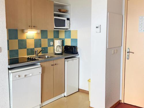 une petite cuisine avec un évier et un micro-ondes dans l'établissement Appartement tout confort avec balcon, skis aux pieds, piscine chauffée, proche commerces et remontées mécaniques - FR-1-267-231, au Corbier