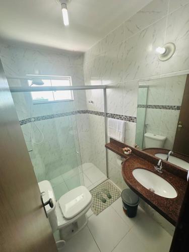 a bathroom with a shower and a toilet and a sink at Apto em Jacumã in Conde