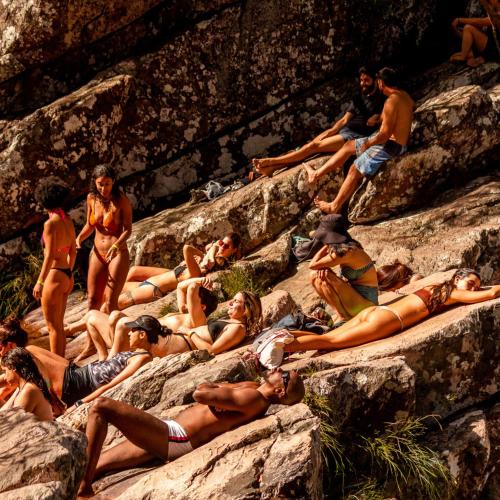a group of people are sitting on rocks at Hostel e Camping Secreto Cerrado Povoado do Moinho Acesso a rios sem custo in Alto Paraíso de Goiás