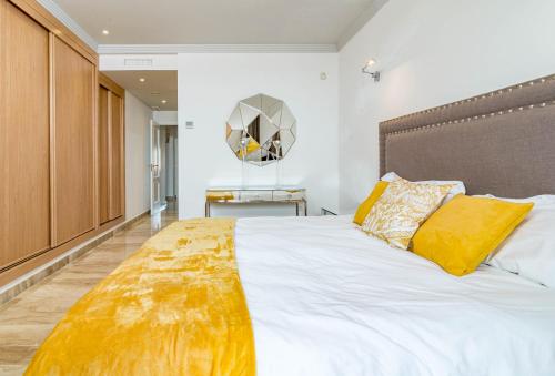 a bedroom with a large white bed with yellow pillows at Luxury 3 bed Duplex Penthouse, 3 mins walk to the beach in Estepona