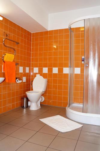 an orange tiled bathroom with a toilet and a shower at Olimpiska Centra Ventspils Hotel in Ventspils