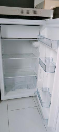 un réfrigérateur vide avec une porte ouverte avec une porte ouverte dans l'établissement Appartement meublé neuf, près de Paris et Beauvais, à Amblainville