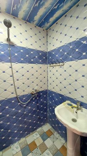 Baño de azulejos azules y blancos con lavabo en Laza guest house mi, en Laza