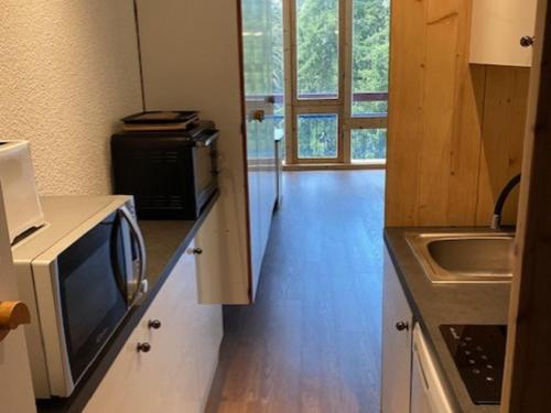 une petite cuisine avec un micro-ondes et un évier dans l'établissement Studio 22m² pour 2 pers. au pied des pistes avec balcon et Wifi - Arc 1800 - FR-1-346-474, à Arc 1800